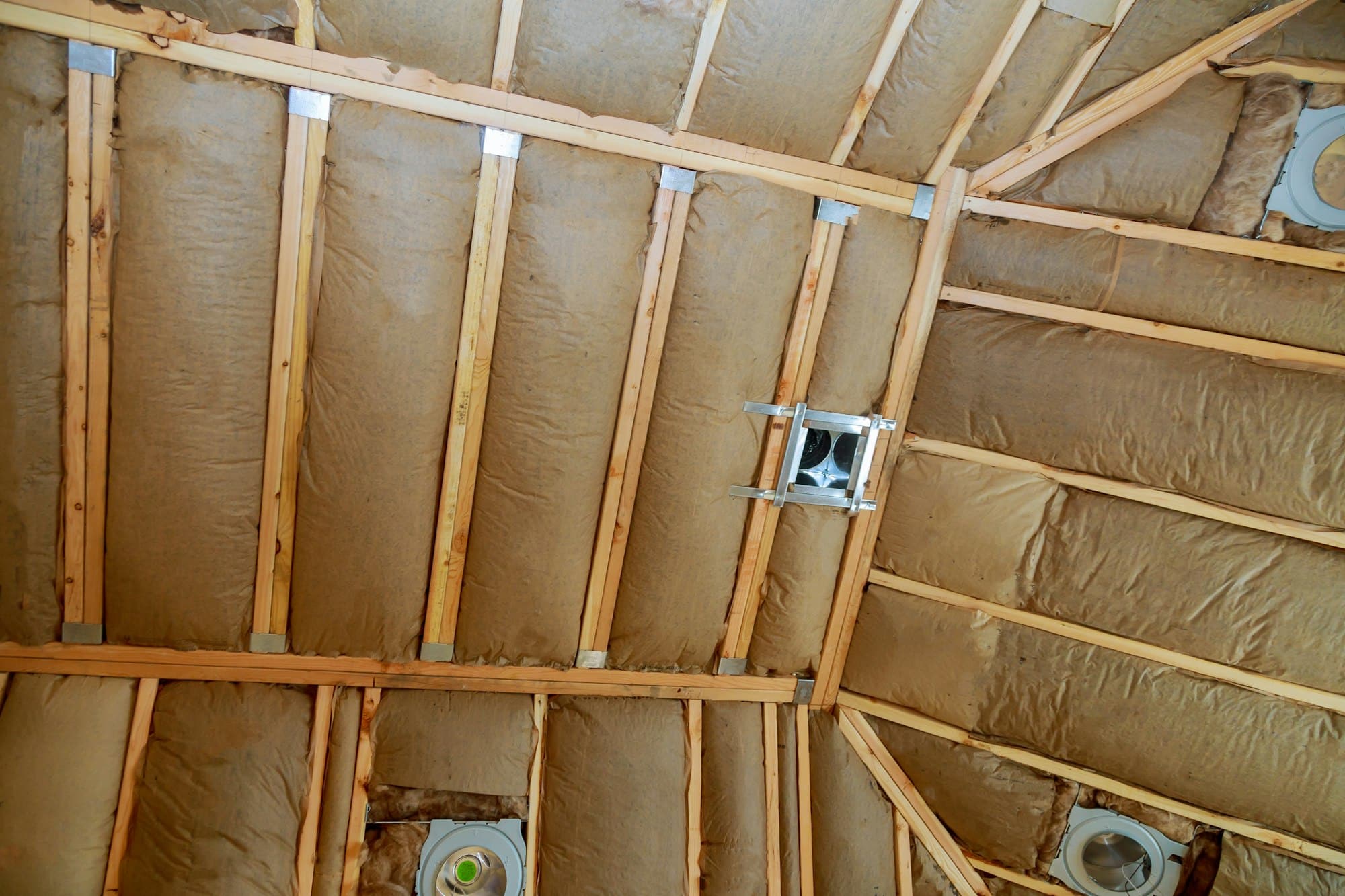 Plafond en construction avec isolation en laine de verre recouverte de pare-vapeur entre les chevrons en bois.